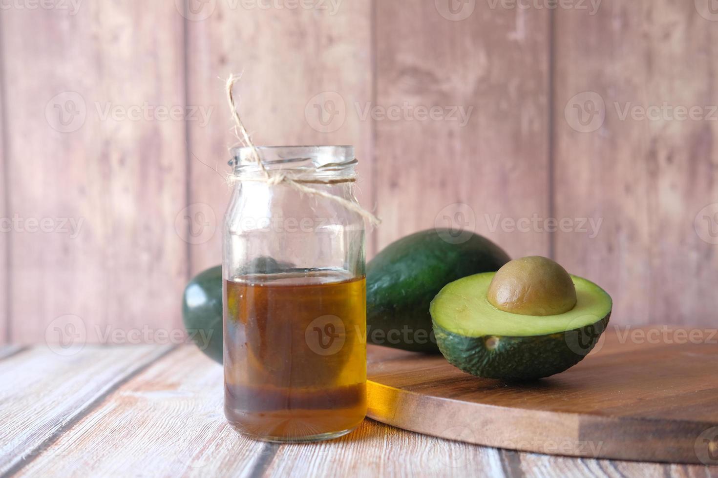 Avocado oil on wooden background photo