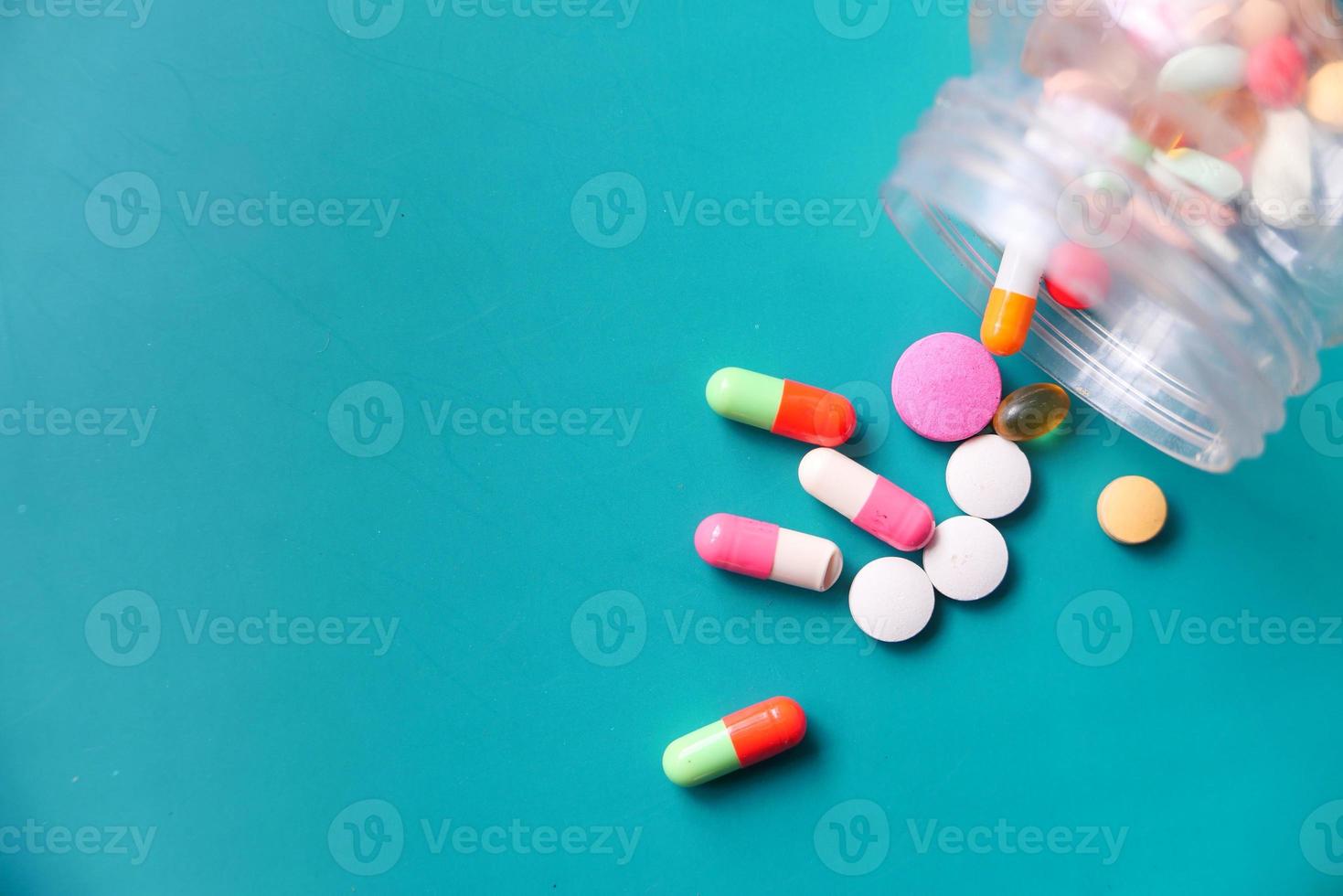 Top view of colorful pills spilling on green background photo