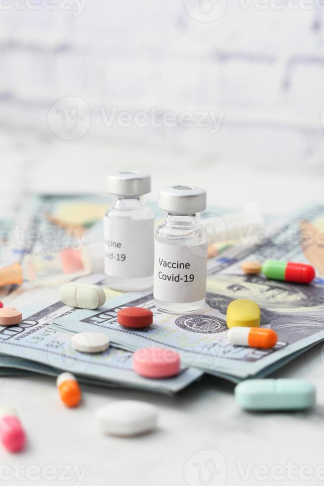 COVID-19 vaccine in bottle with pills and US dollars photo
