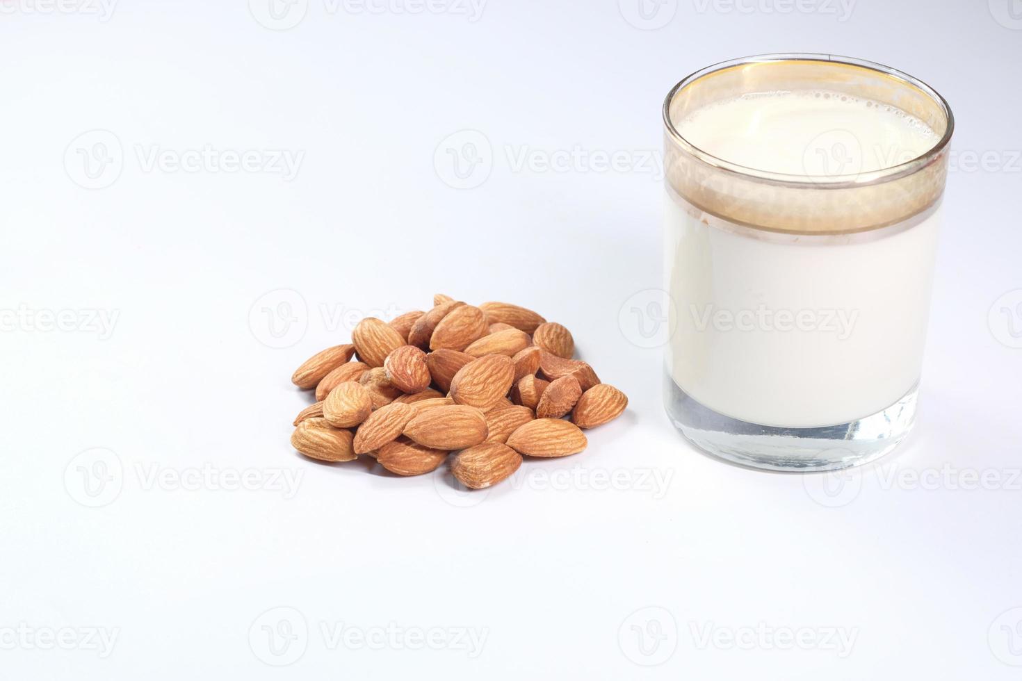 almendras y un vaso de leche sobre fondo blanco foto