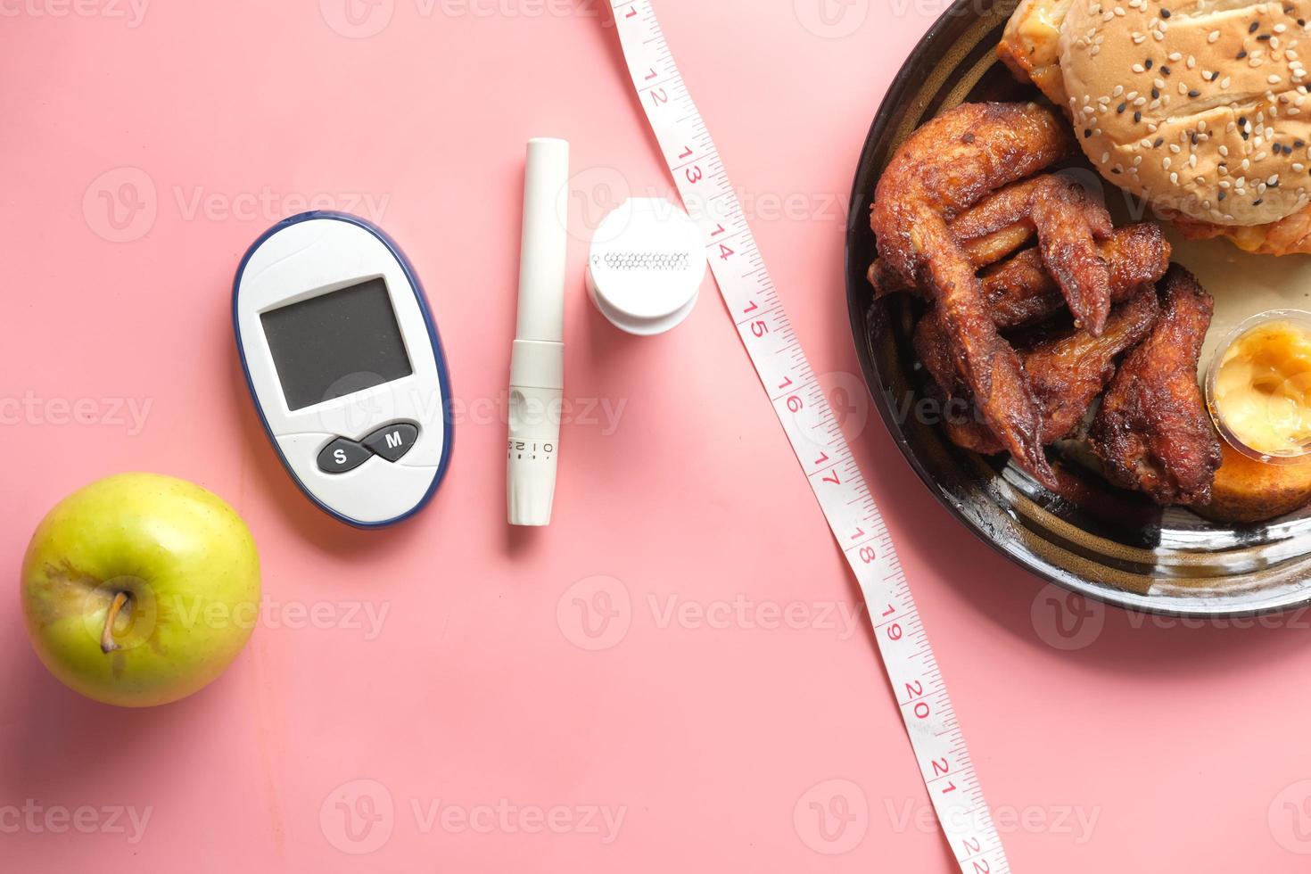 Herramientas de medición para diabéticos con manzana y harina sobre fondo rosa foto