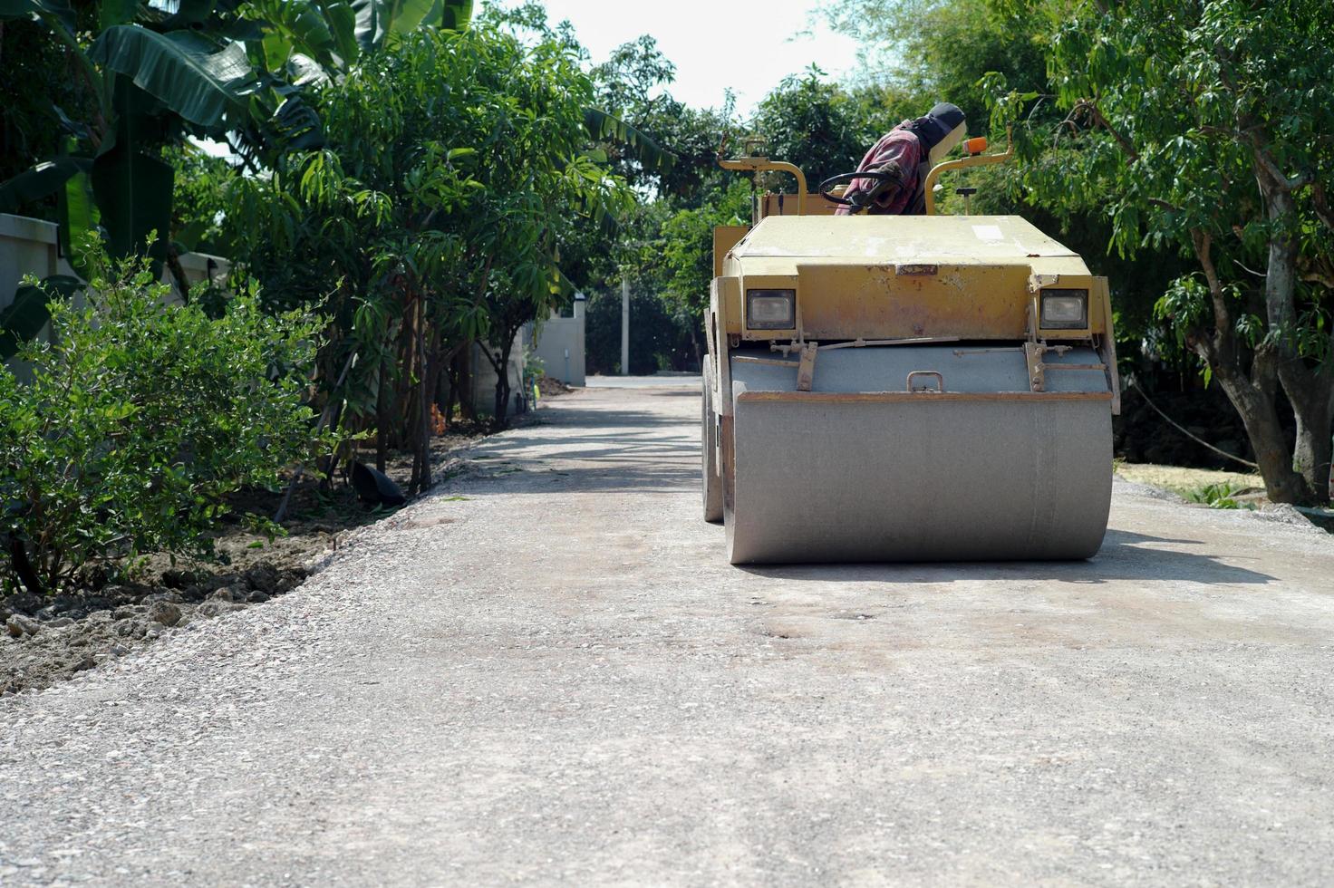 Worker drives the road roller on the crash stone road for preparaing the surface photo