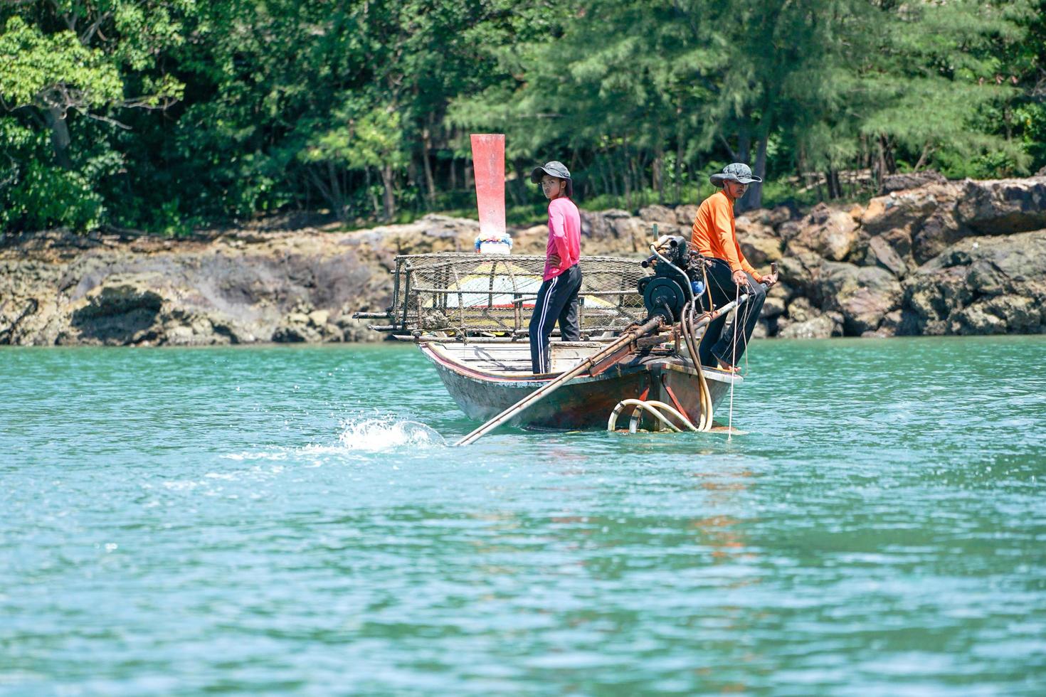 krabi, tailandia 2019: los pescadores conducen el tradicional bote de cola larga y encuentran peces con herramientas foto