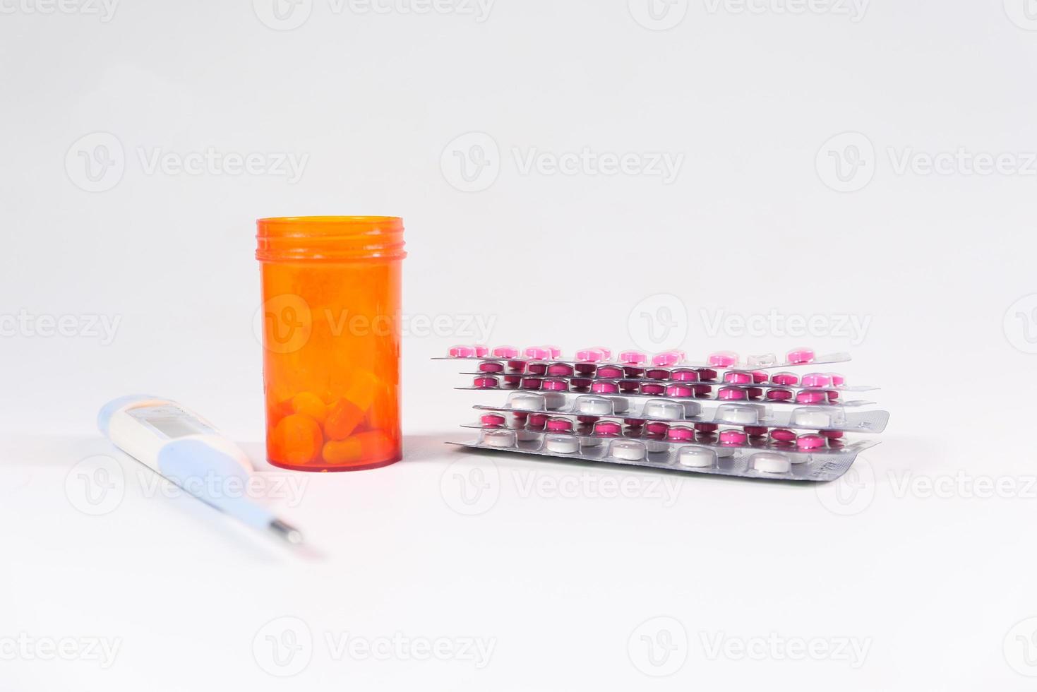 Thermometer, pill container, and blister pack on white background photo