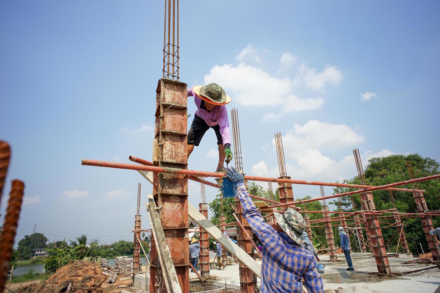 Ratchaburi, Tailandia 2018: un grupo de trabajadores construye los cimientos de la casa vertiendo el cemento mezclado en el modelo de madera en el sitio de construcción foto