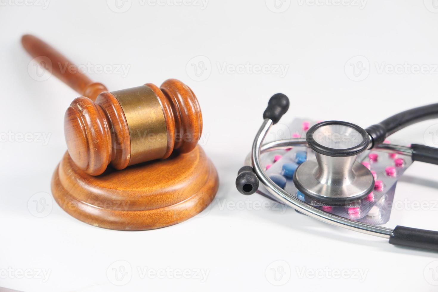 Gavel, stethoscope, and pills on white background photo