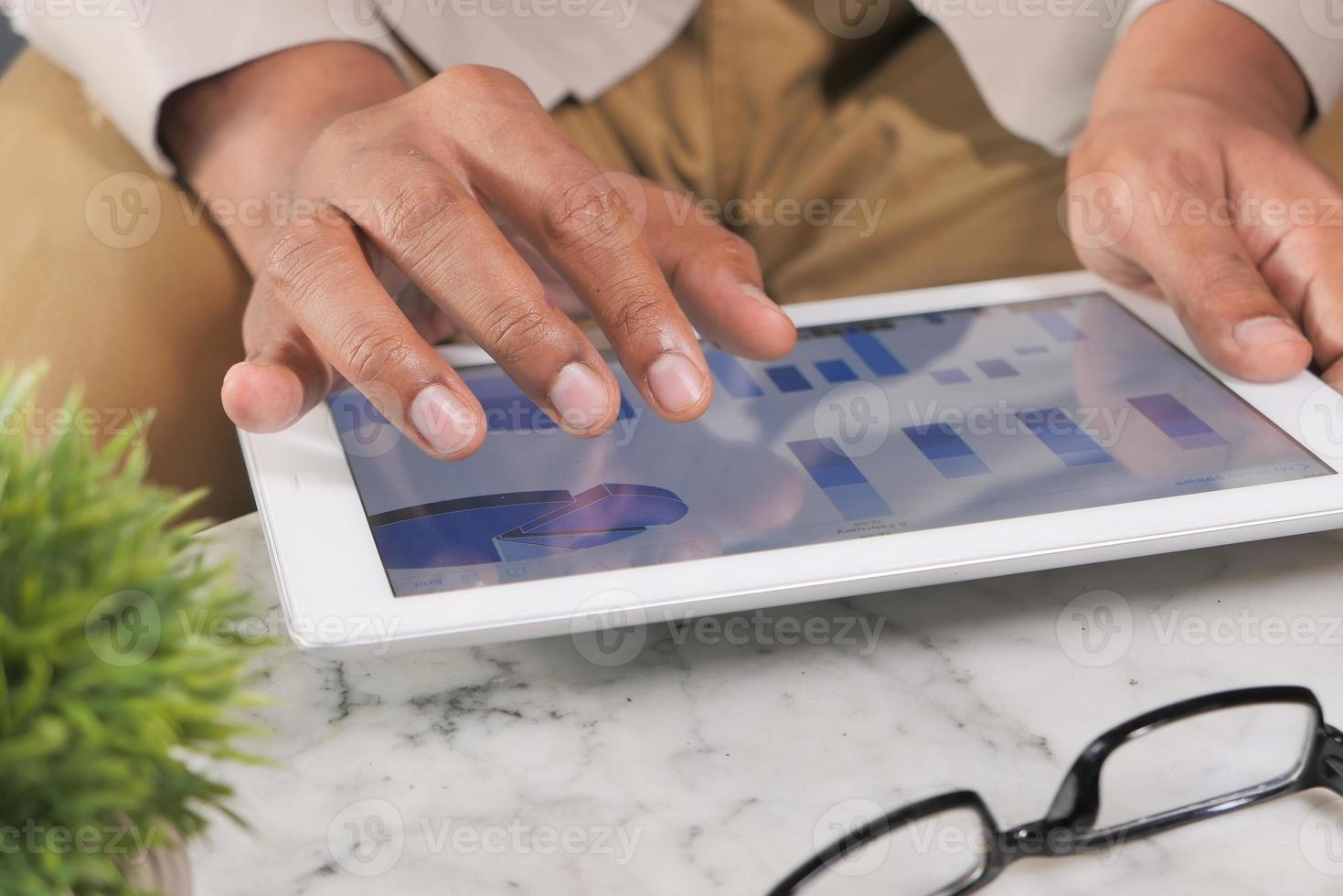 La mano del hombre trabajando en tableta digital en el escritorio de oficina foto