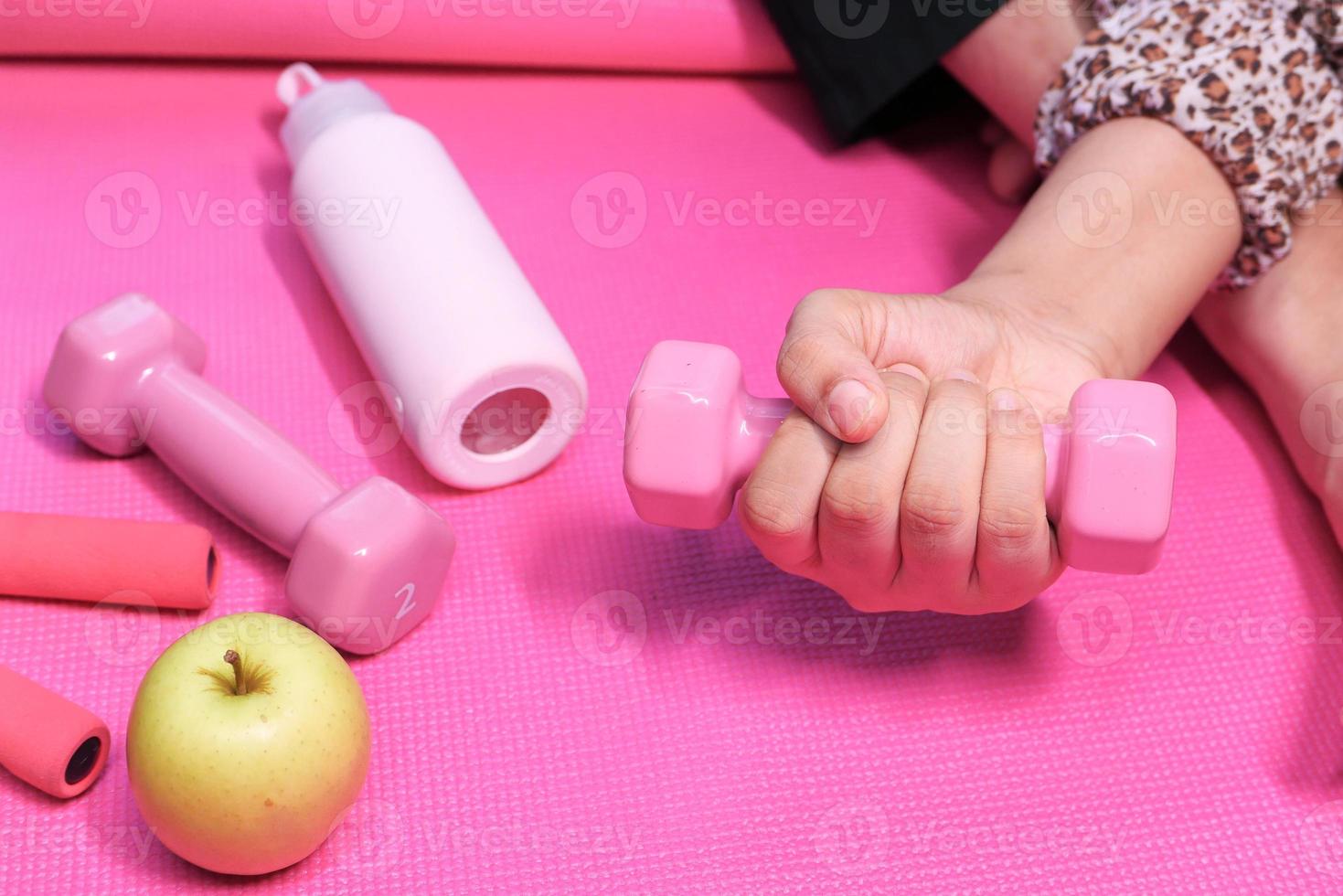 Close up of woman holding pink dumbbell photo