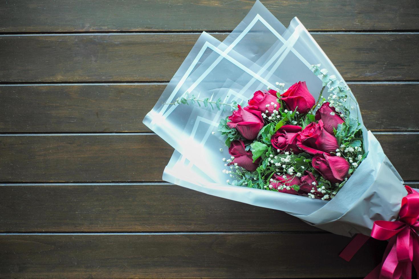 Vista superior del ramo de rosas rojas florecidas sobre la mesa de madera foto