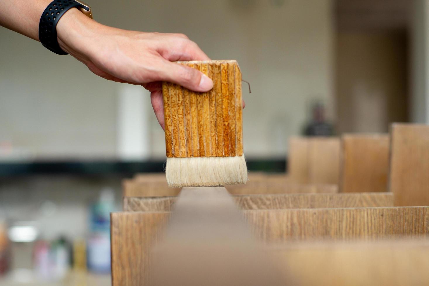 El enfoque selectivo en la mano de un carpintero sosteniendo un pincel de madera foto