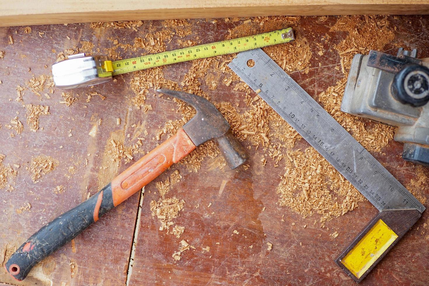 Top view of carpentry tools on dirty wooden desk with sawdust photo