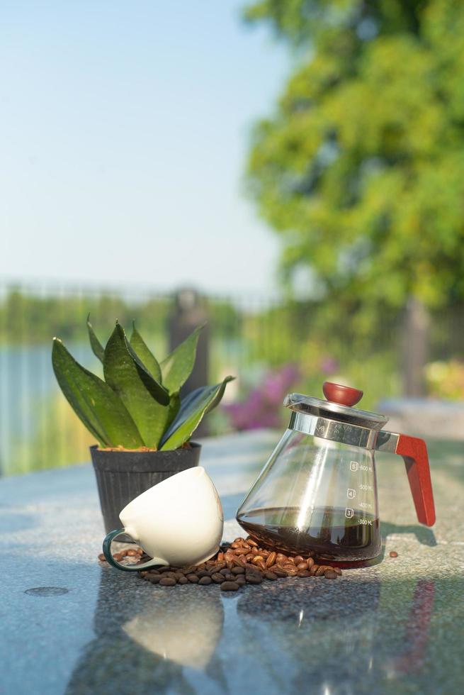 Retrato de un frasco de vidrio con café dentro y taza vacía sobre la mesa foto