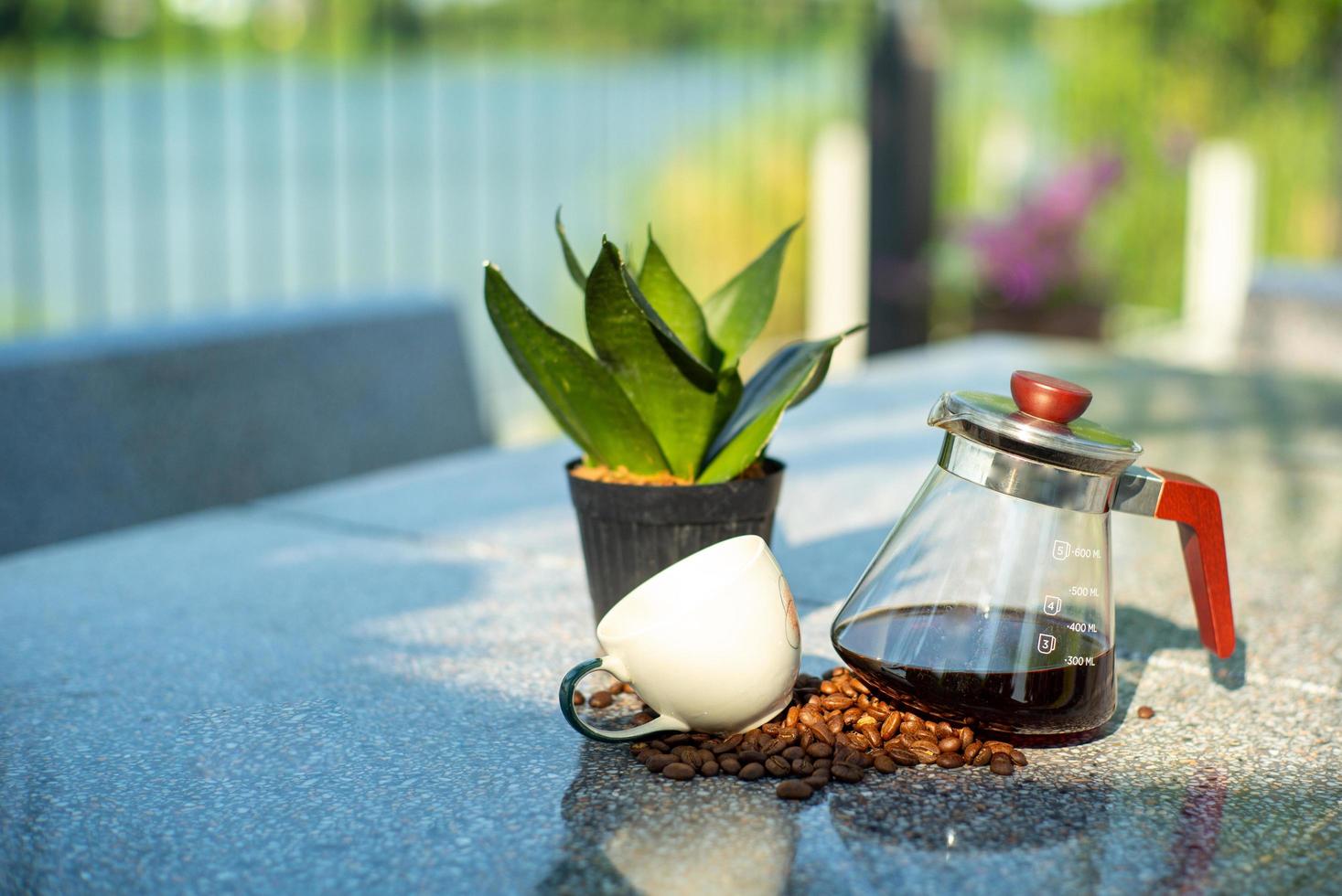 Portrait of glass jar with coffee inside and empty cup on table at the outdoor garden photo