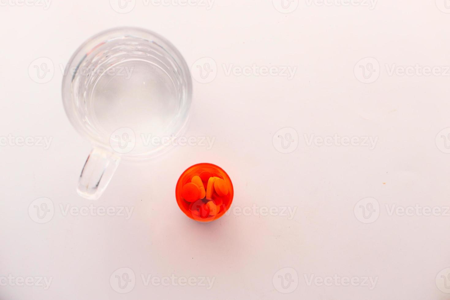 Top view of pill container and glass of water on white background photo