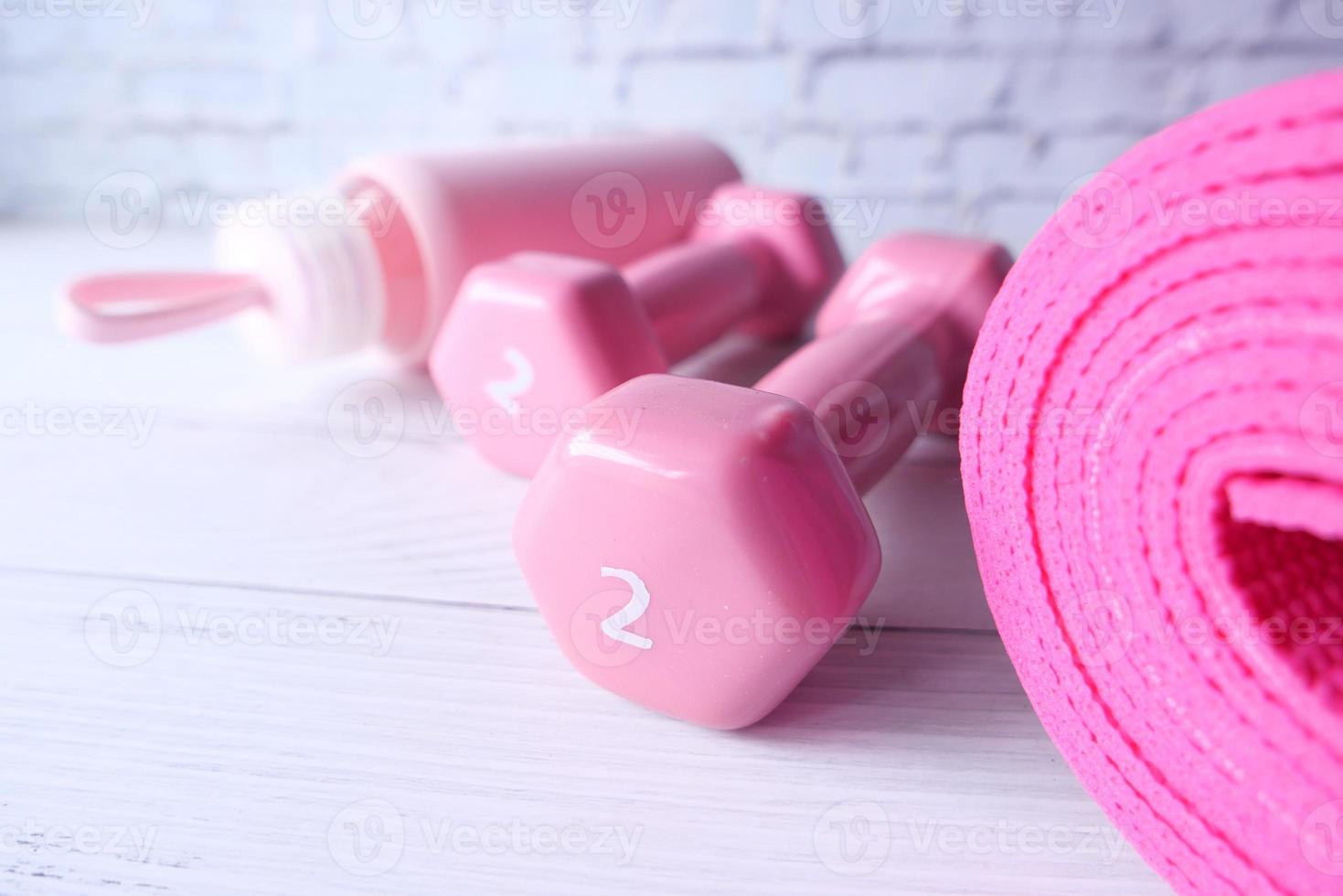 Pink color dumbbell and exercise mats on white background photo