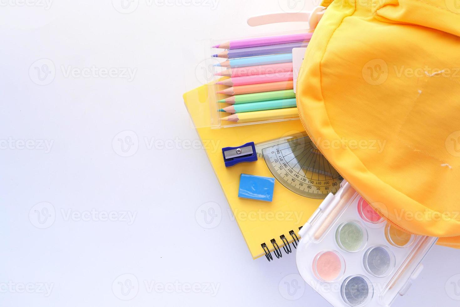 mochila amarilla con útiles escolares y espacio de copia foto