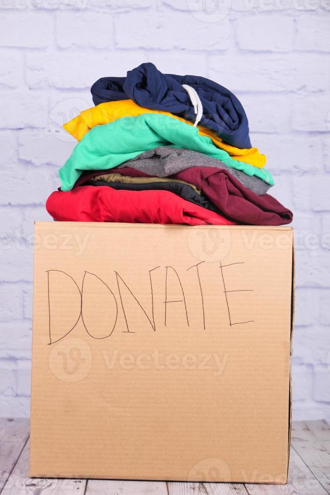 Caja de donación con ropa en una mesa de madera. foto