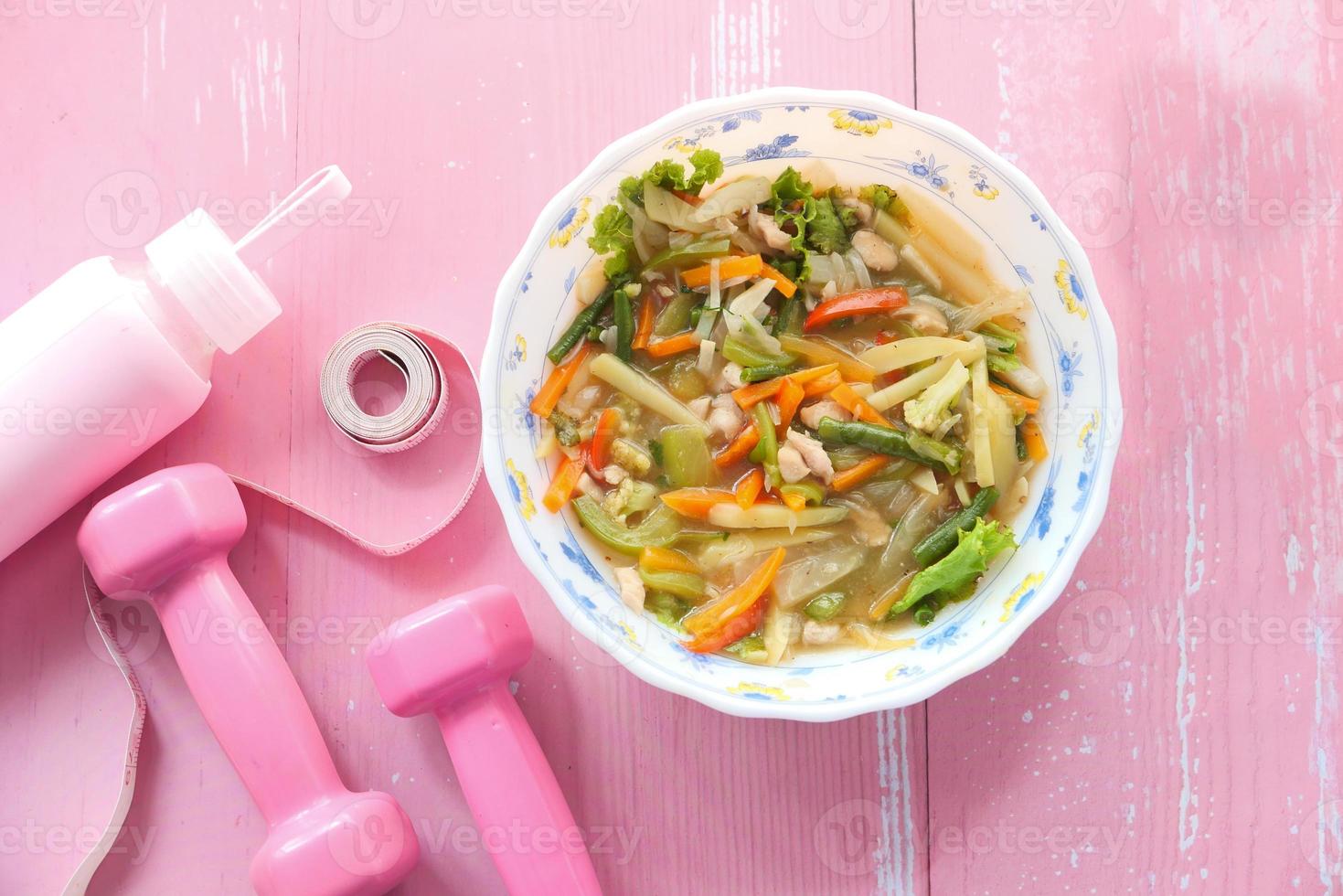 sopa de verduras y equipo de entrenamiento rosa en la mesa foto