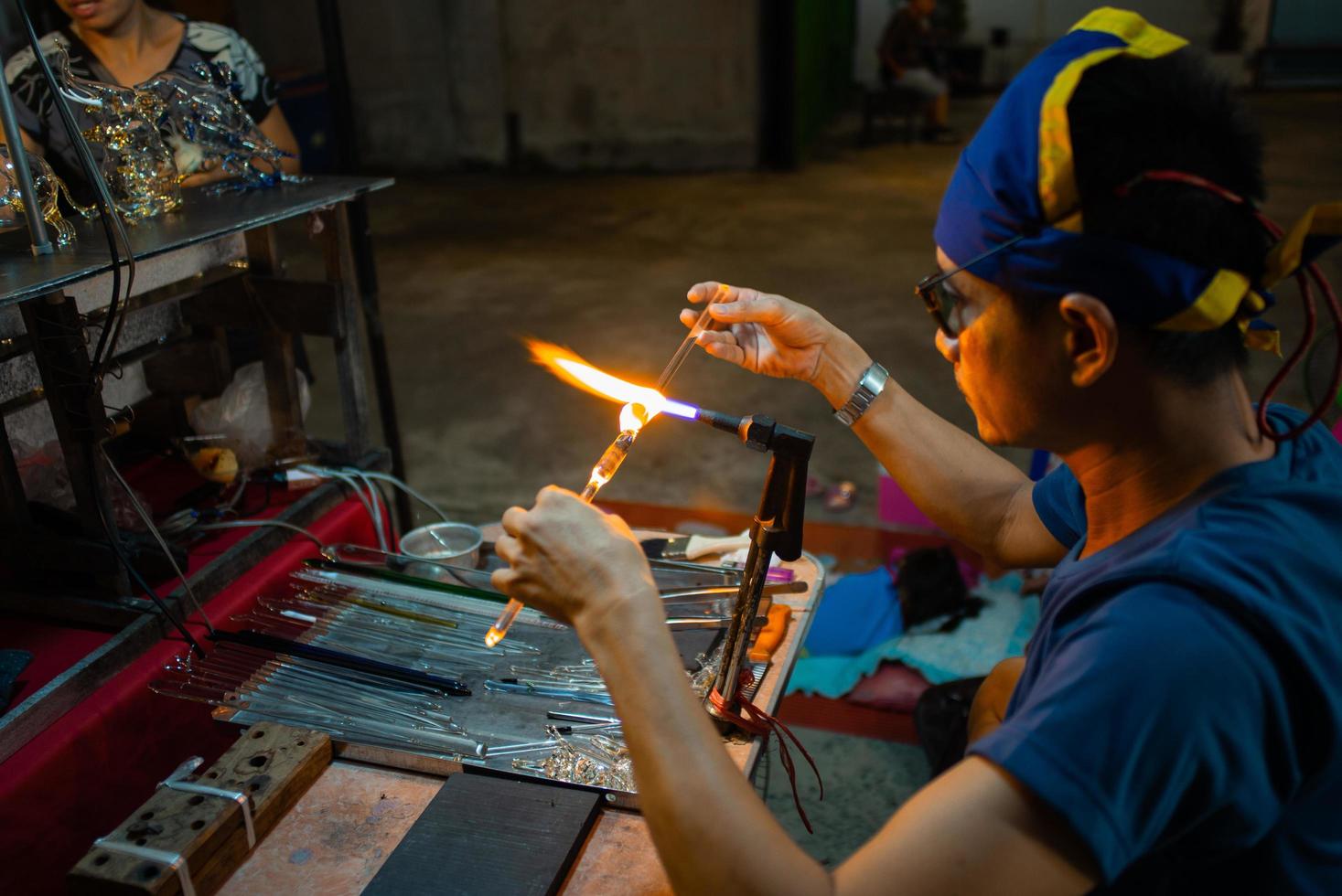 Hua Hin, Tailandia 2018: el trabajador está fabricando productos artesanales fundiendo y soplando las barras de vidrio. foto