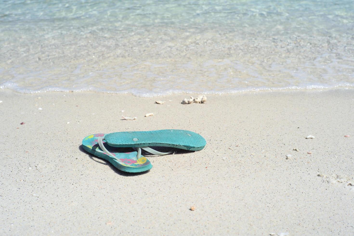 Closeup pair of old sandals on the white sand beach photo