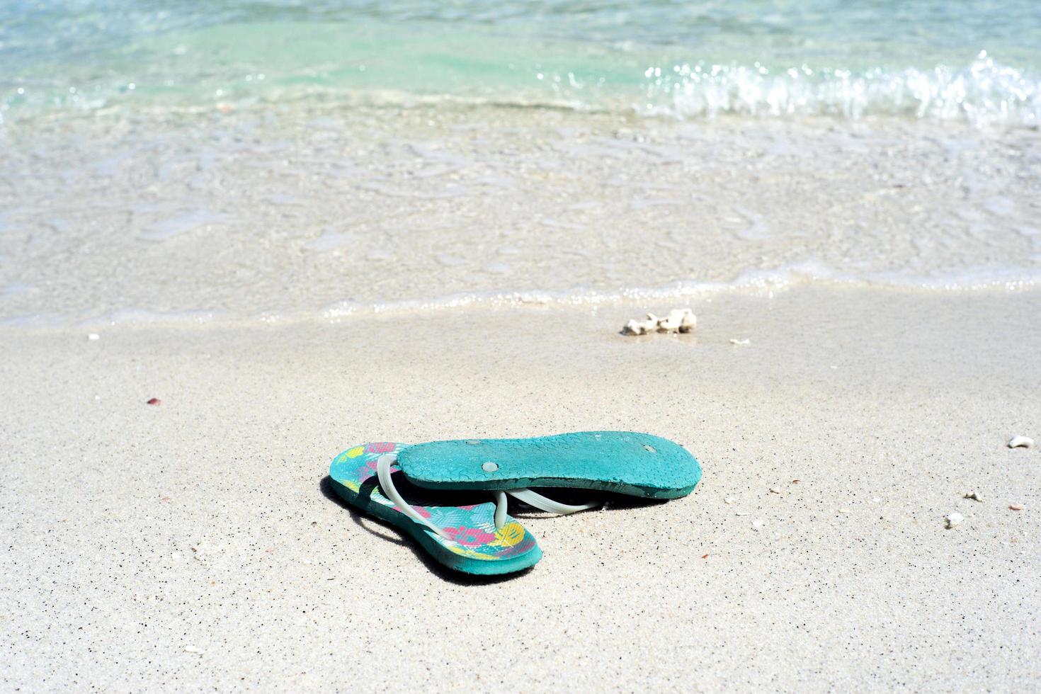 Closeup pair of old sandals on the white sand beach photo