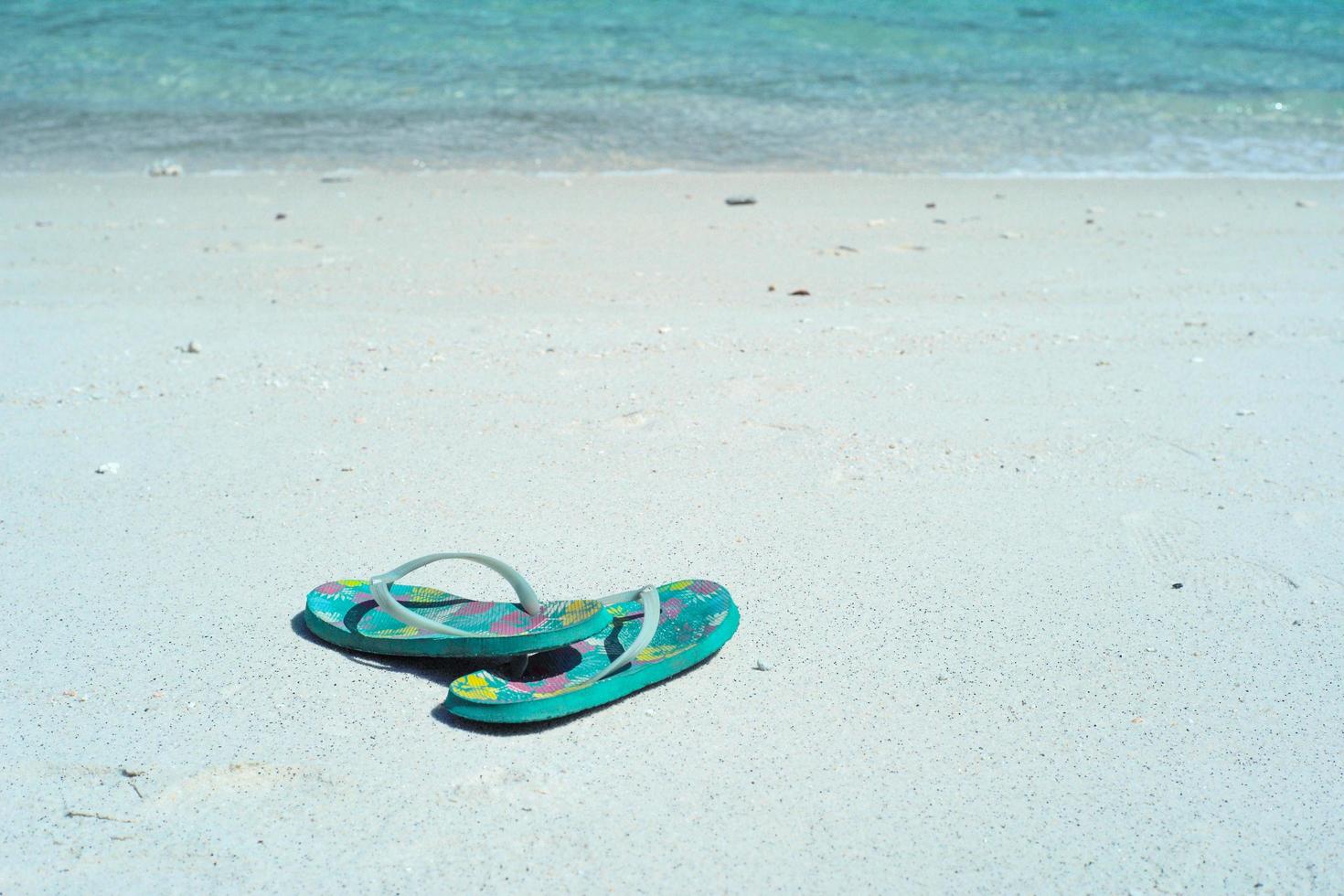 Closeup pair of old sandals on the white sand beach photo