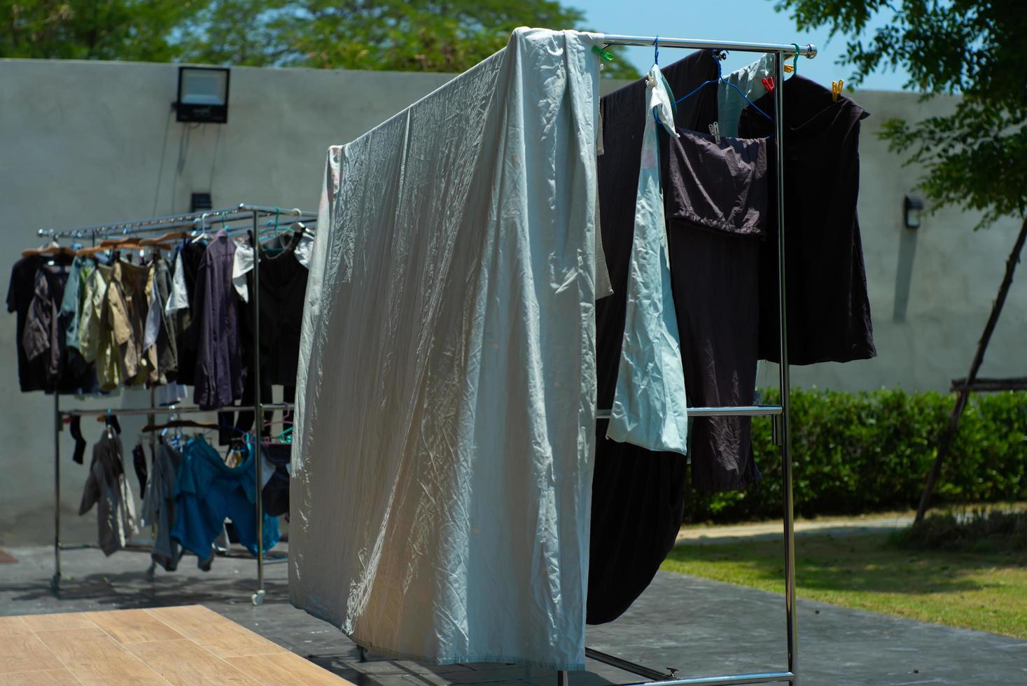 Many pieces of clothes hanging on the stainless rack for drying with the sunlight. photo