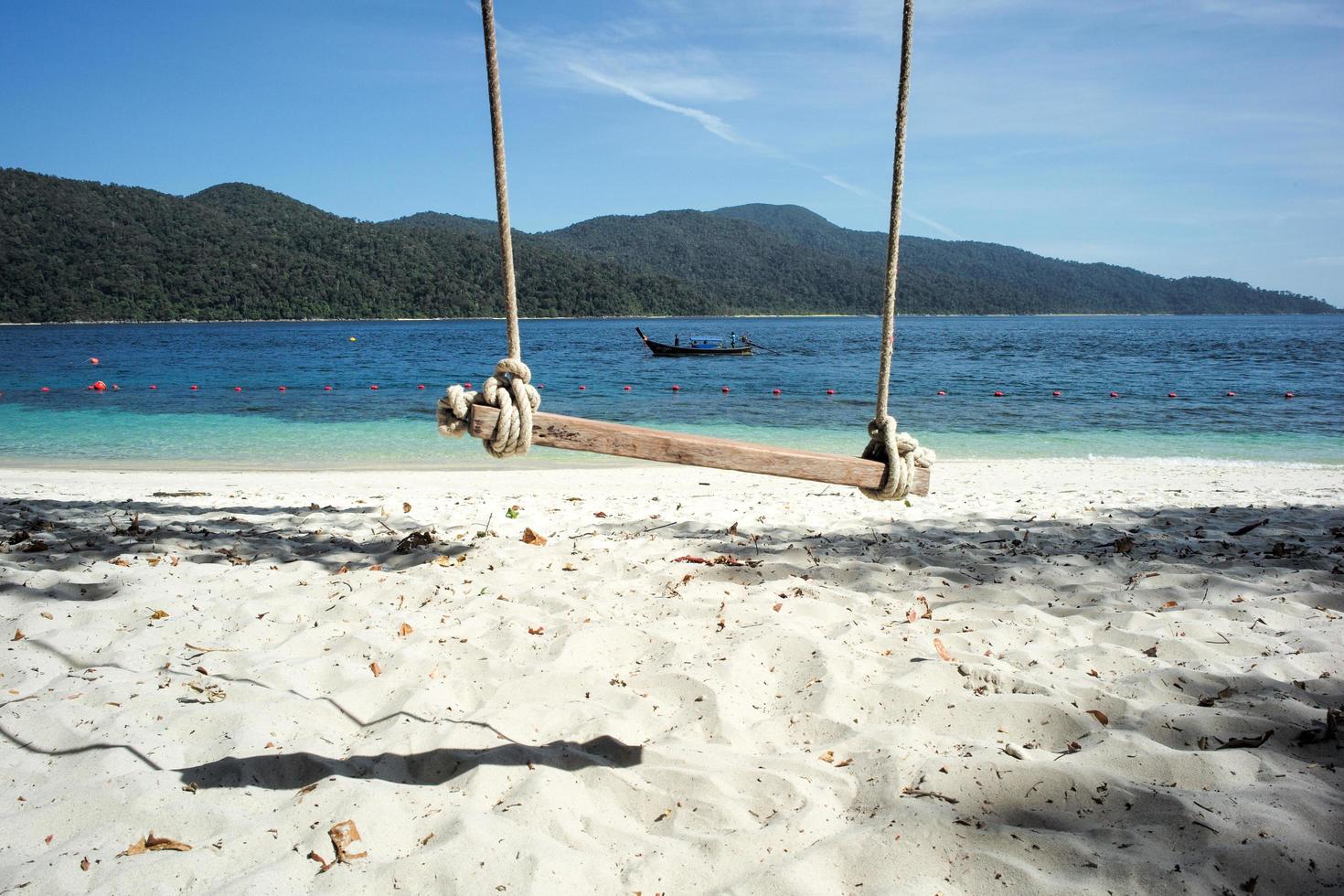 Selective focus on old wooden swing hanging from the tree with sea background photo