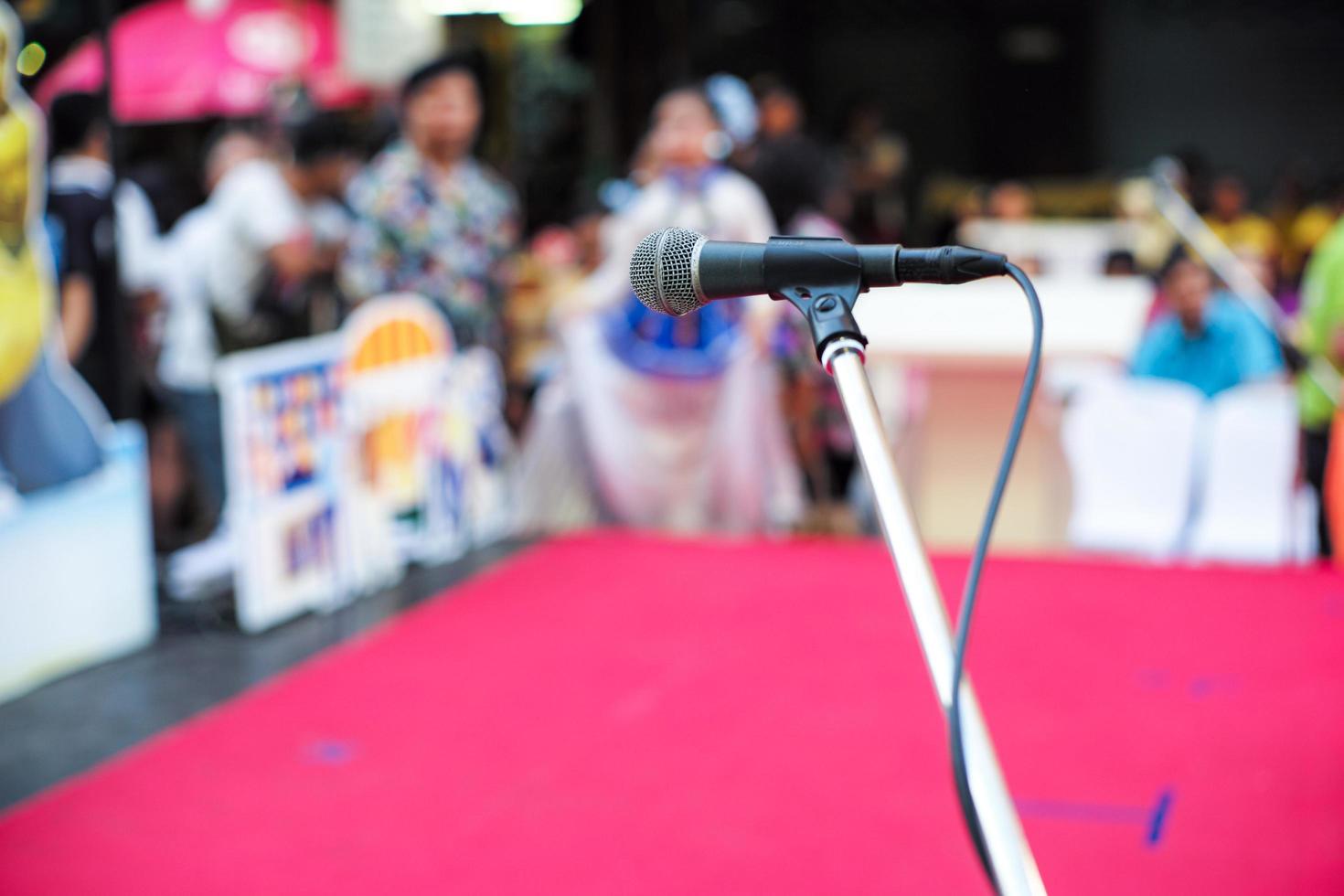 Selective focus on microphone on stage with blurred crowd of people in background photo