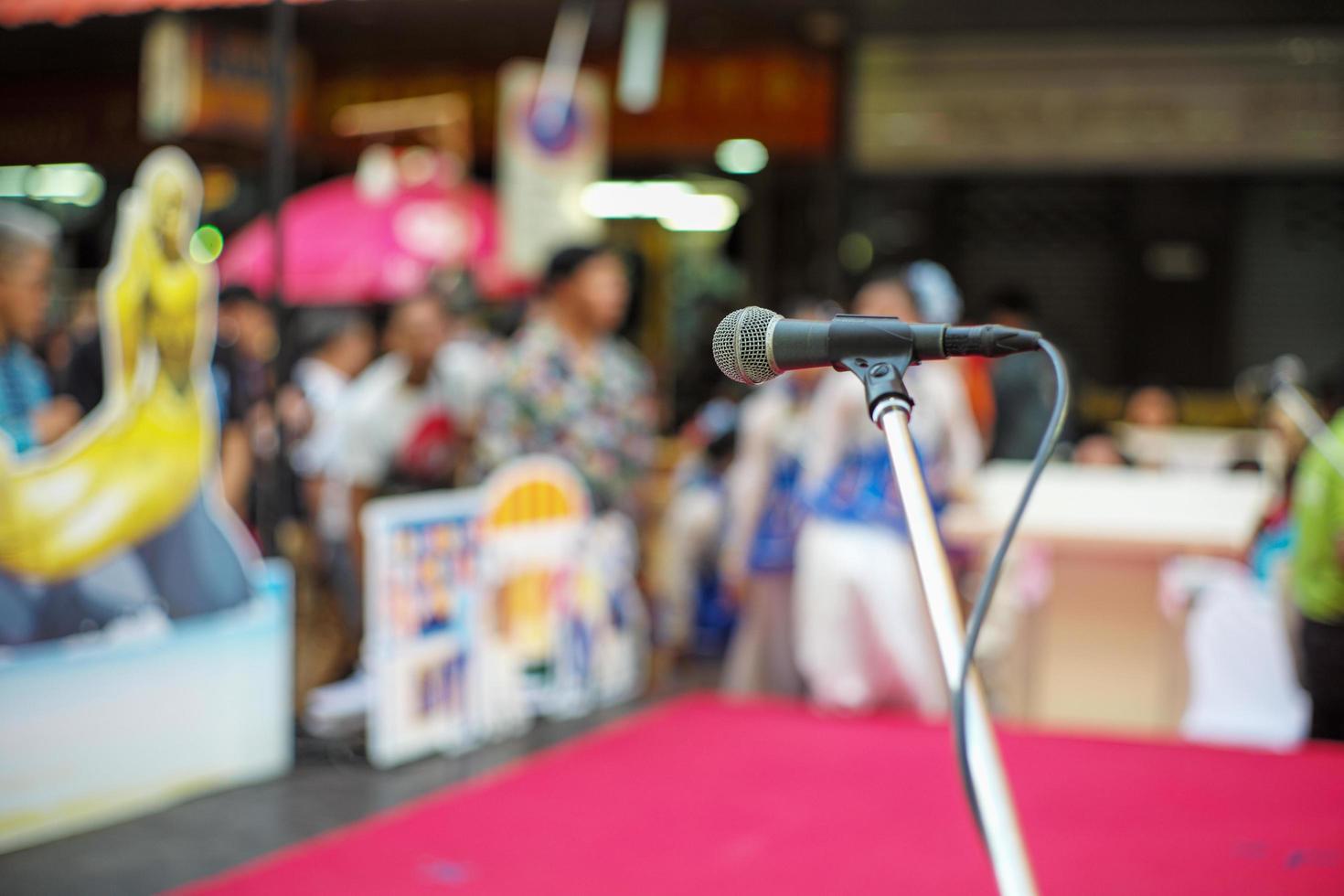 Selective focus on microphone on stage with blurred crowd of people in background photo