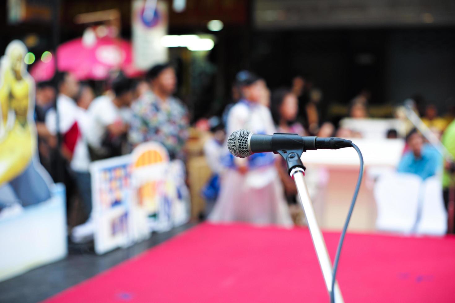 Selective focus on microphone on stage with blurred crowd of people in background photo