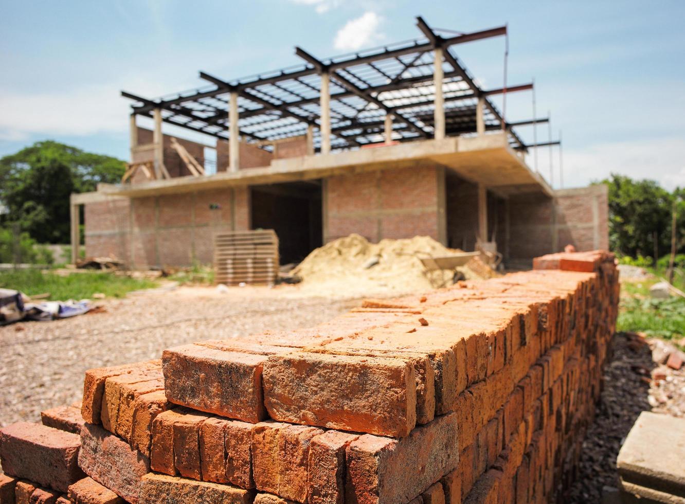 Montón de ladrillos rojos con borrosa casa en construcción foto