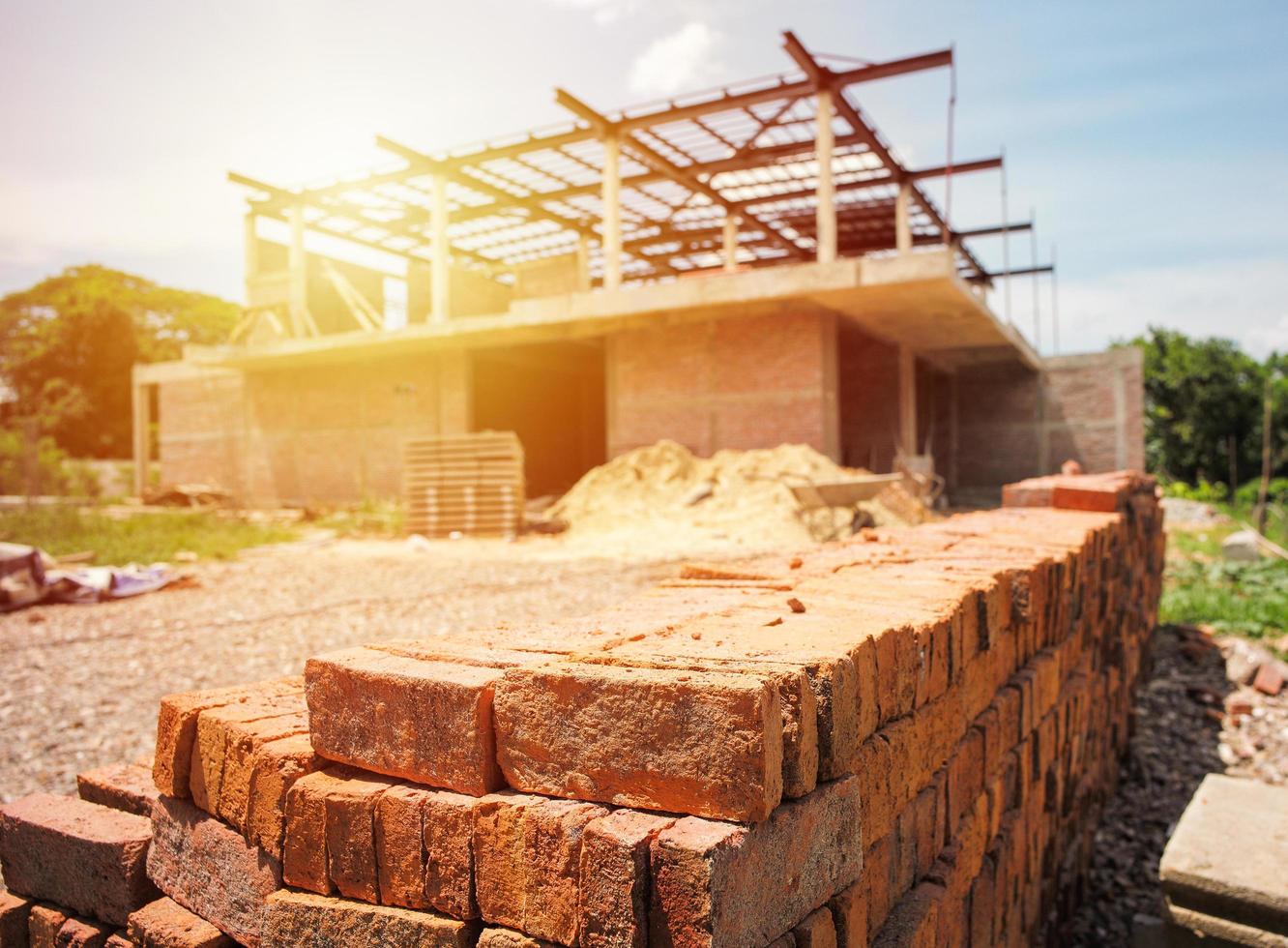 Montón de ladrillos rojos con borrosa casa en construcción foto