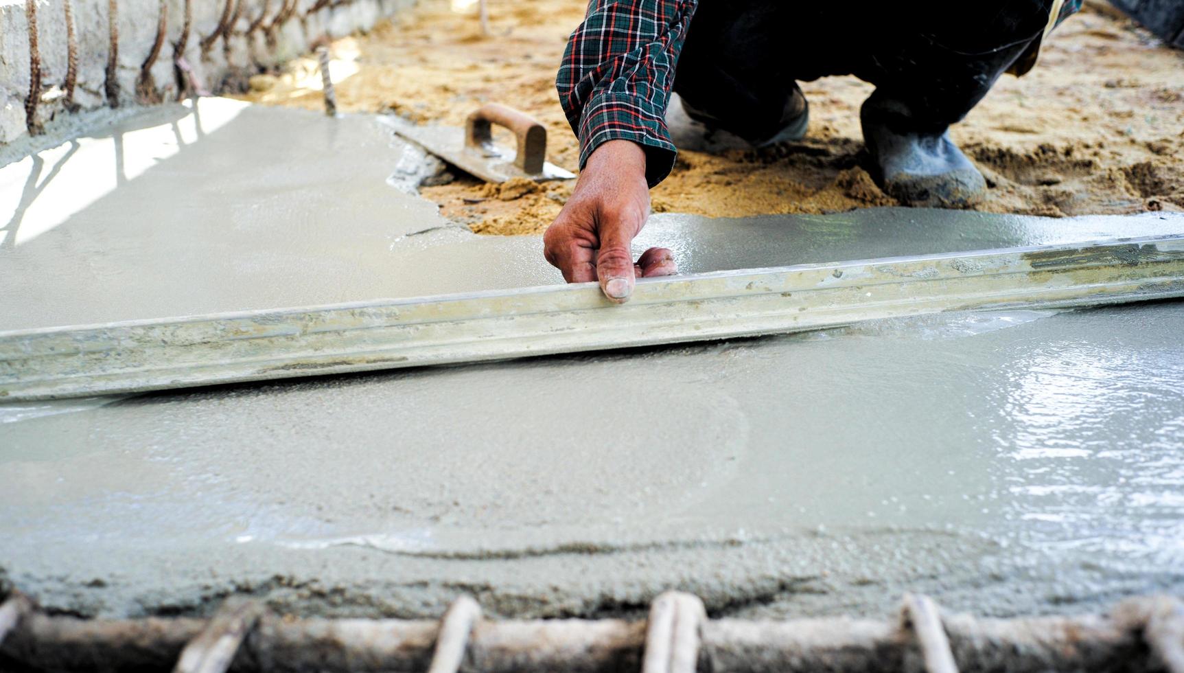 Worker using wooden trowel for leveling the concrete floor photo