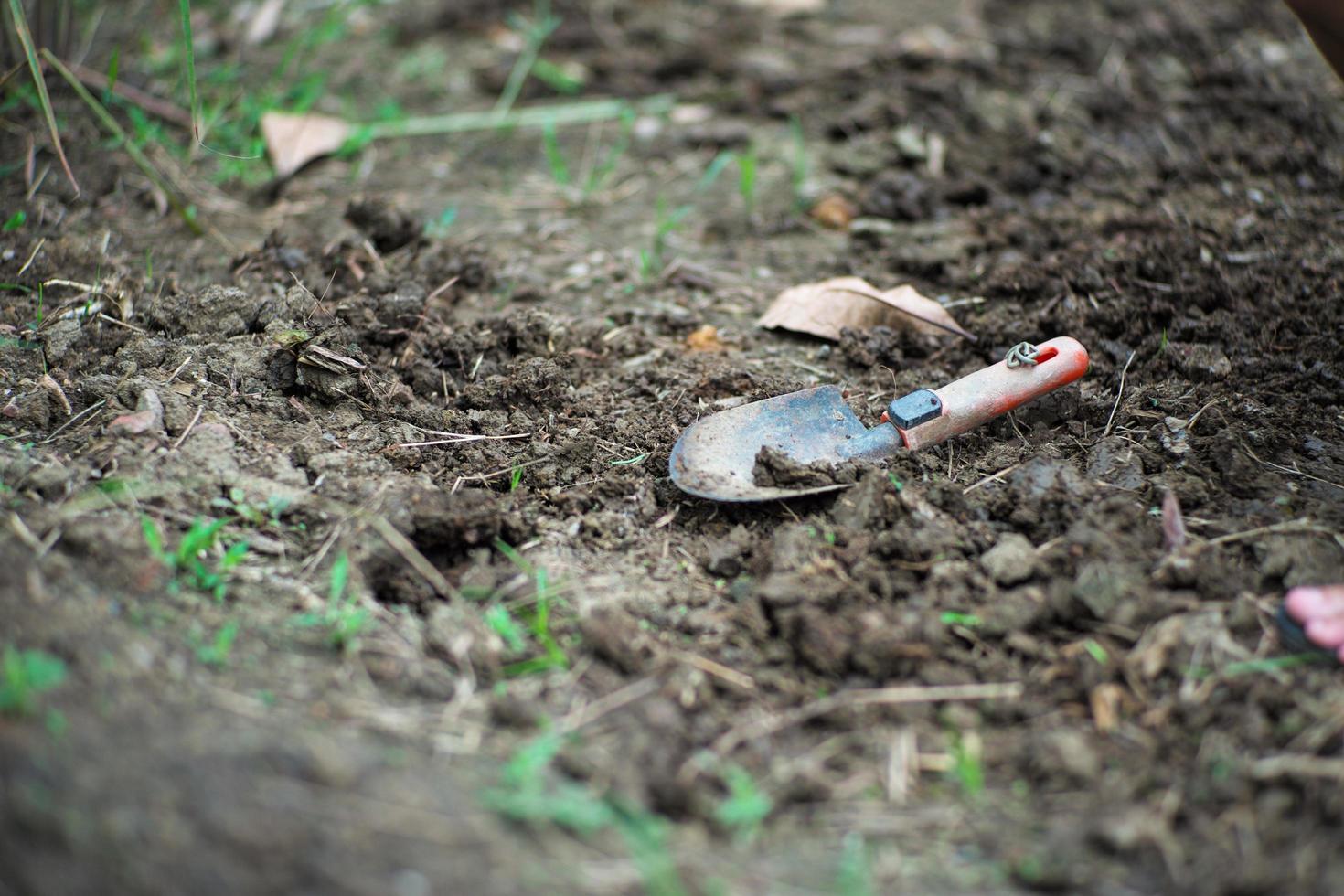 Closeup of dirty planting spoon on the soil land with blurred foreground of grass photo
