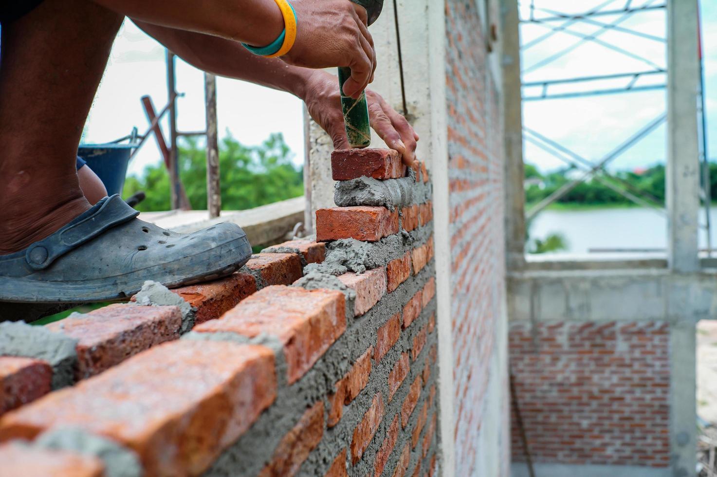 Worker uses the trowel for installing the red bricks on the wall photo