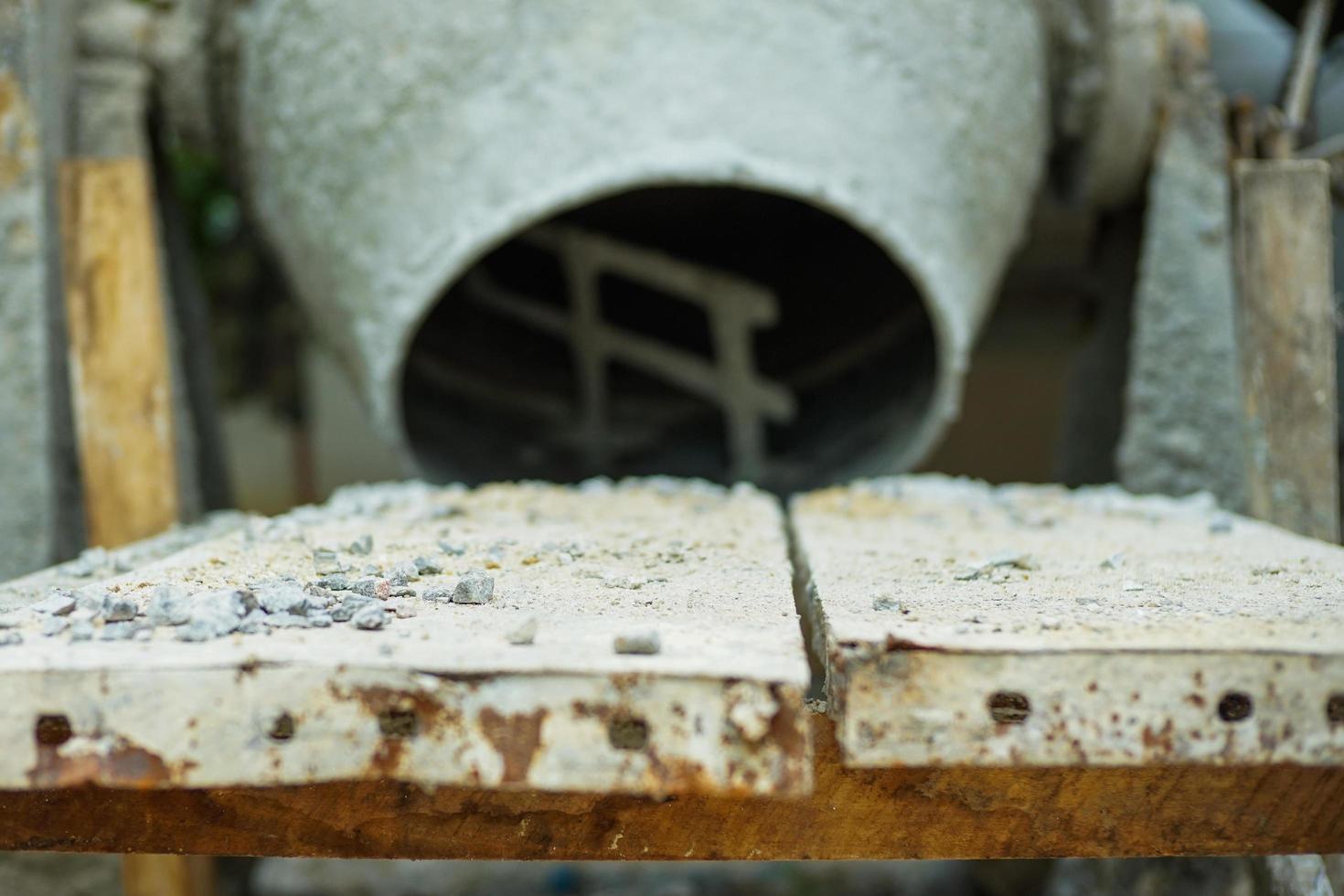 Selective focus on group of crashed stones on the steel plate with blurred concrete mixer photo