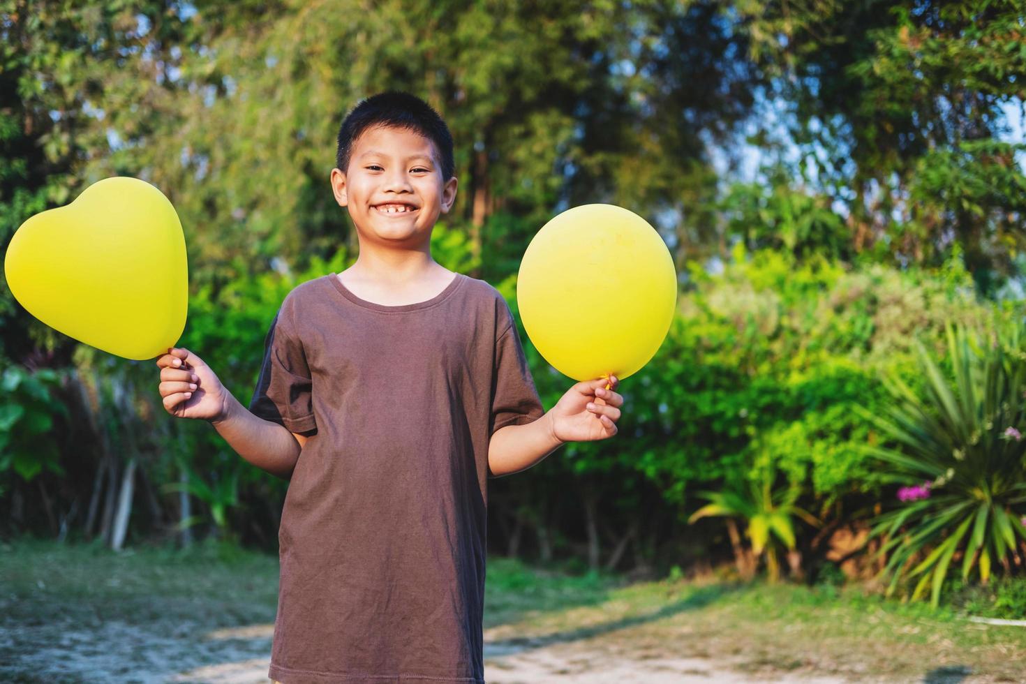 niño feliz sosteniendo globos amarillos foto