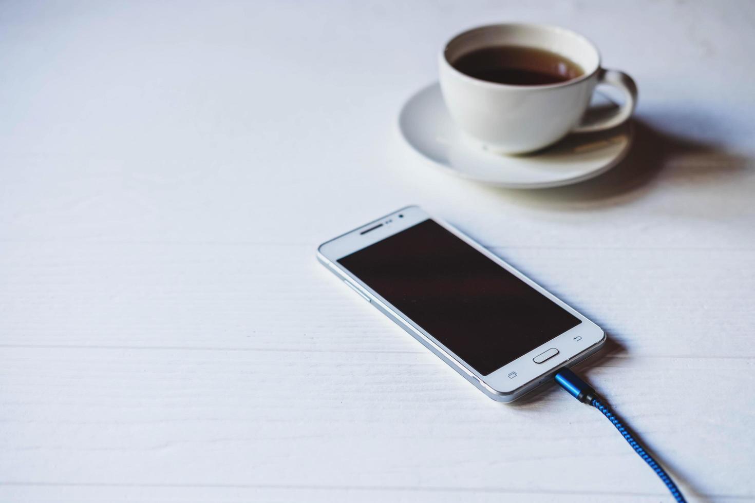 teléfono en cargador con café foto