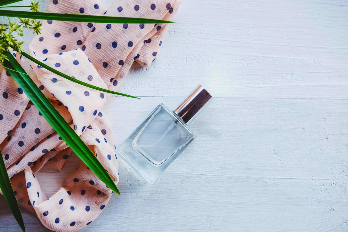 Flat lay of perfume with a plant and ribbon photo