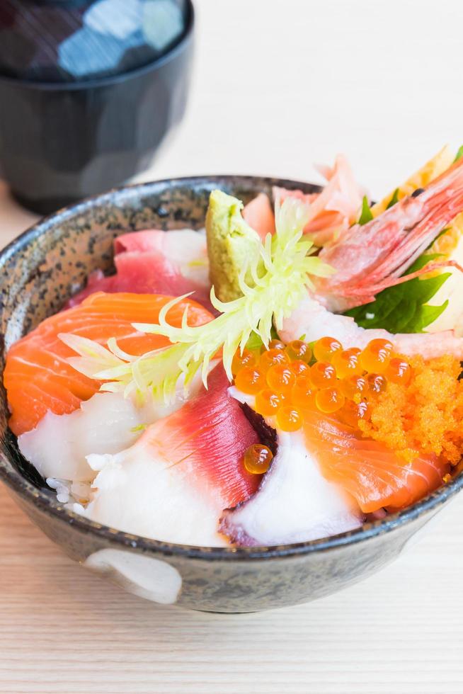 tazón de arroz japonés con sashimi de mariscos encima foto