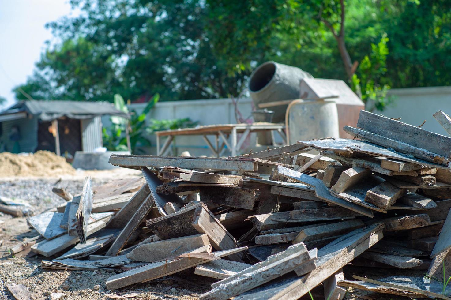 Closeup pile of useless wood at the construction site with blurred concrete mixer in background photo