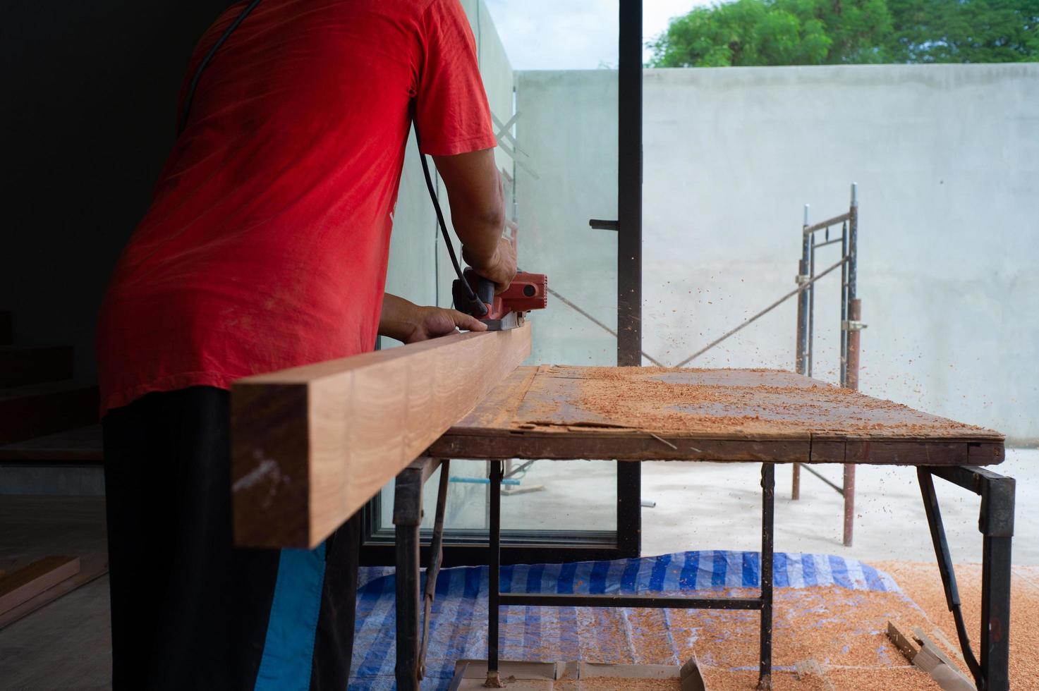 Primer plano de la mano del carpintero sostiene la herramienta eléctrica fregando la superficie de la madera foto