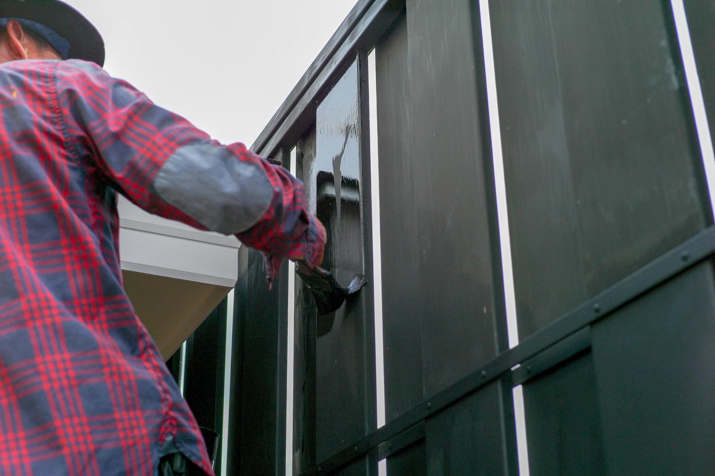 Motion blurred hand of worker painting the steel fence. Repair and maintenence concept photo