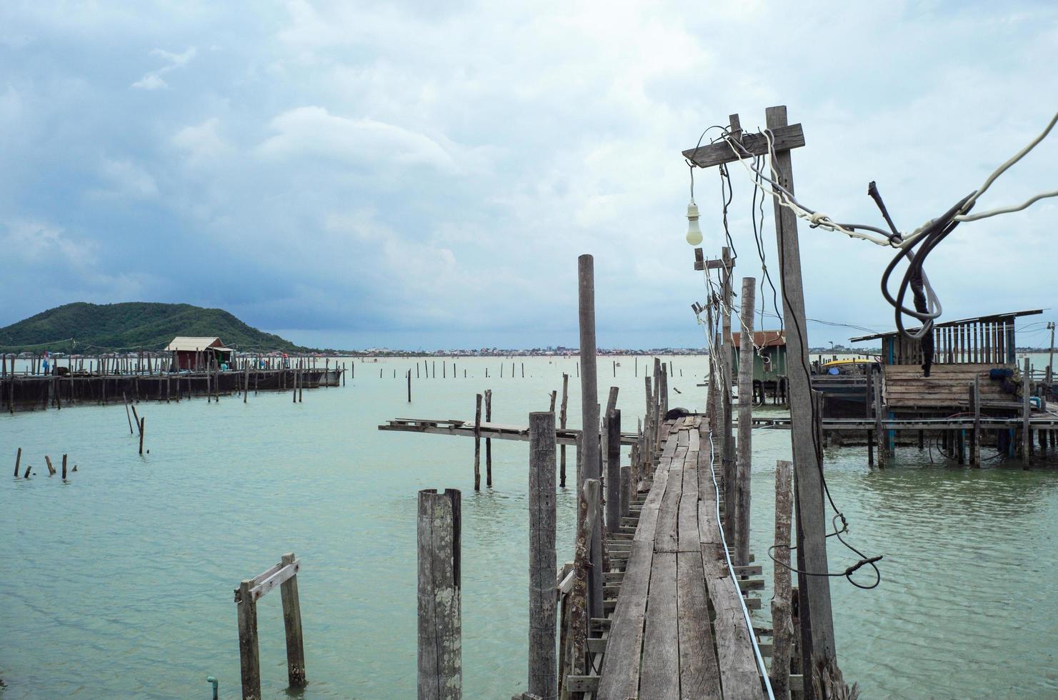 Perspective wooden walkway into the sea with cloudy sky background photo