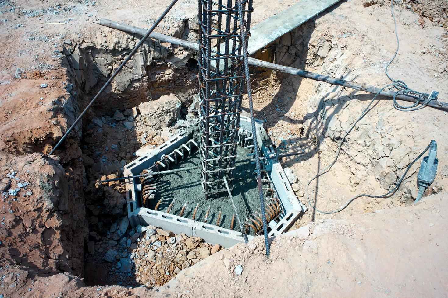 Poste de acero de refuerzo en el agujero de hormigón para la estructura del edificio de la casa foto