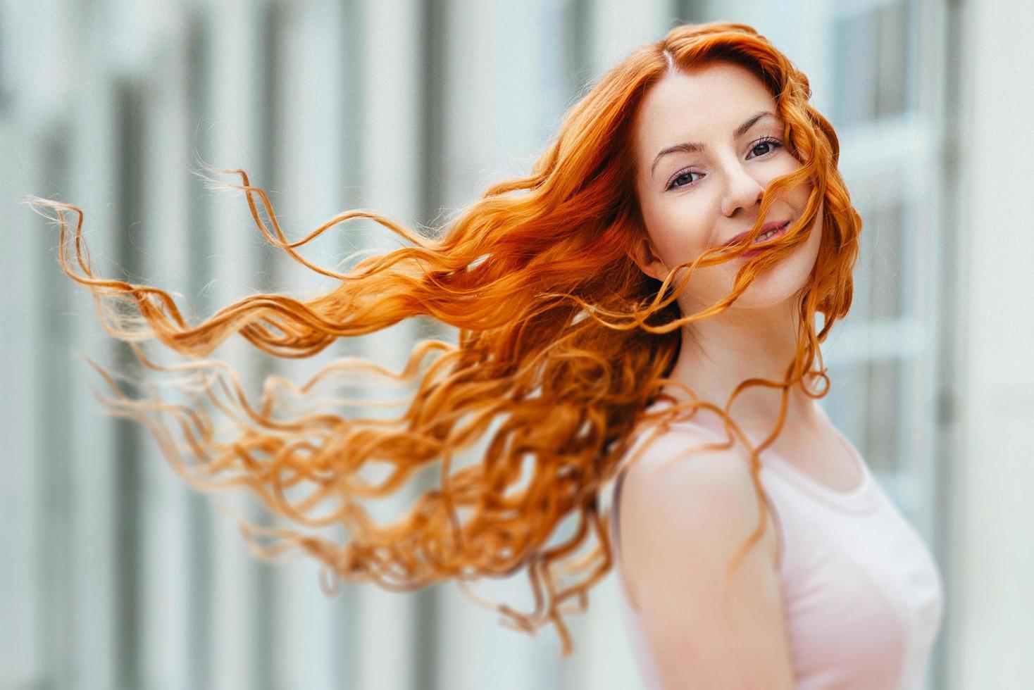 Red-haired young girl walking in a park between trees and architectural objects photo