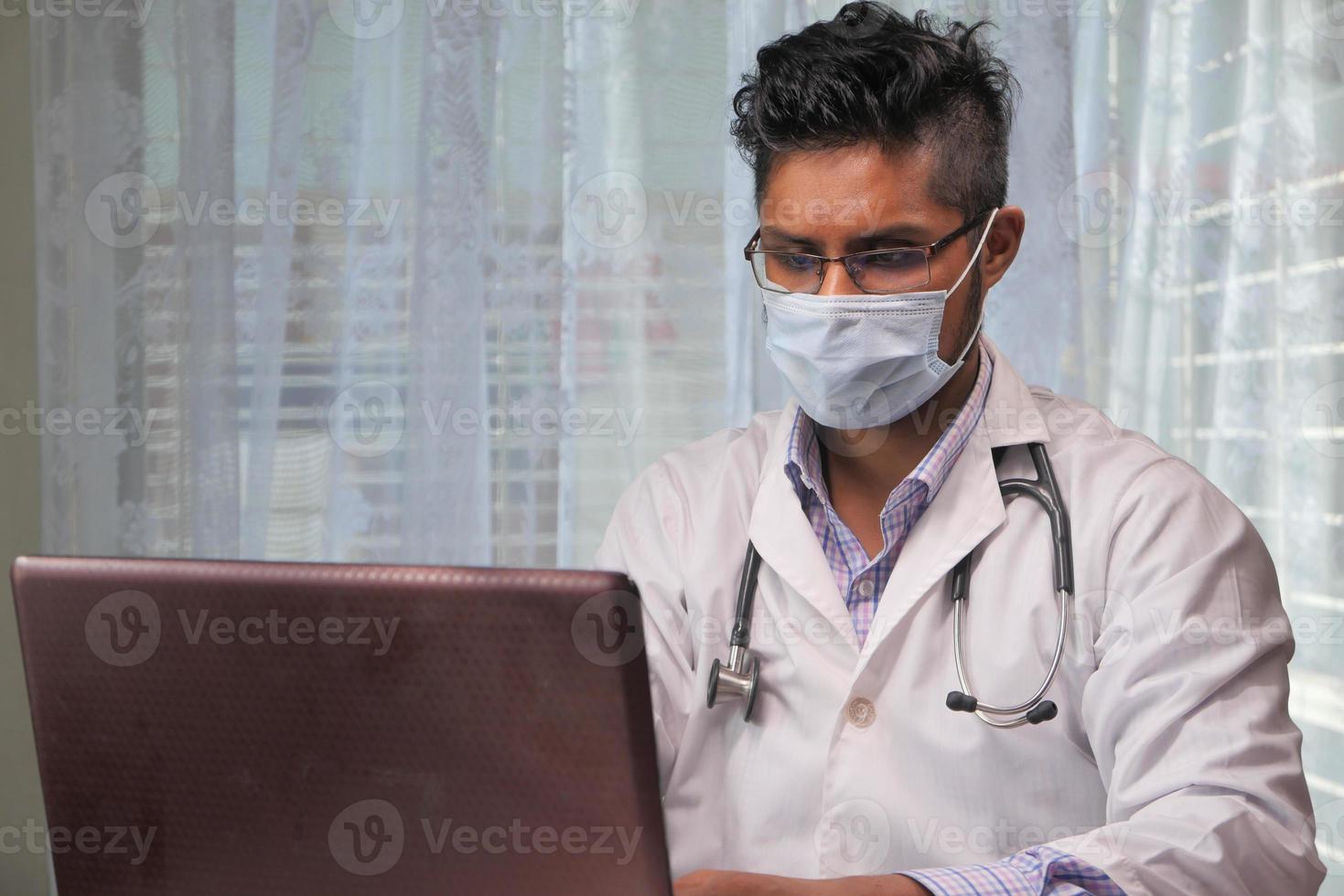 Doctor en máscara protectora usando laptop en el hospital foto