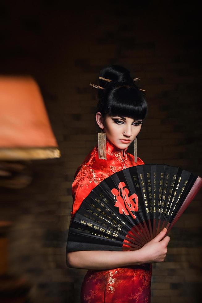 chica con un vestido rojo de seda japonesa qipao en una habitación oscura foto