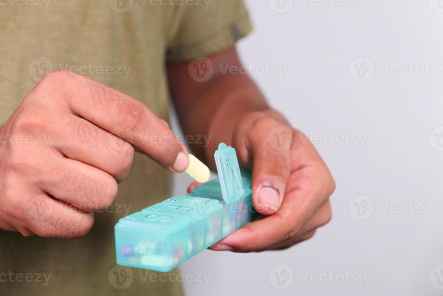 Cerca de la mano del hombre tomando pastillas de pastillero foto